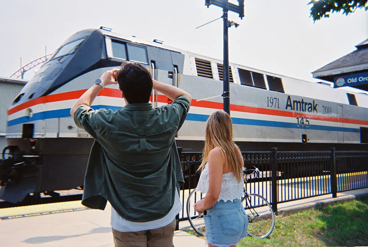 girl and guy taking photos of train