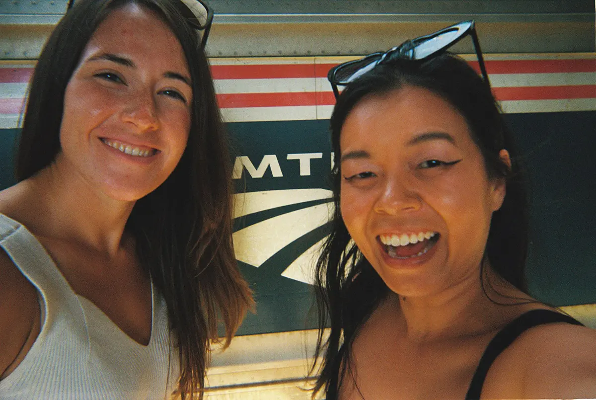 two girls smiling in front of train